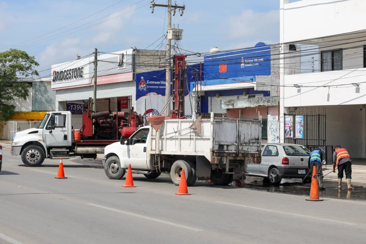 Municipal crew cleaning a storm drain well on a Cancún avenue