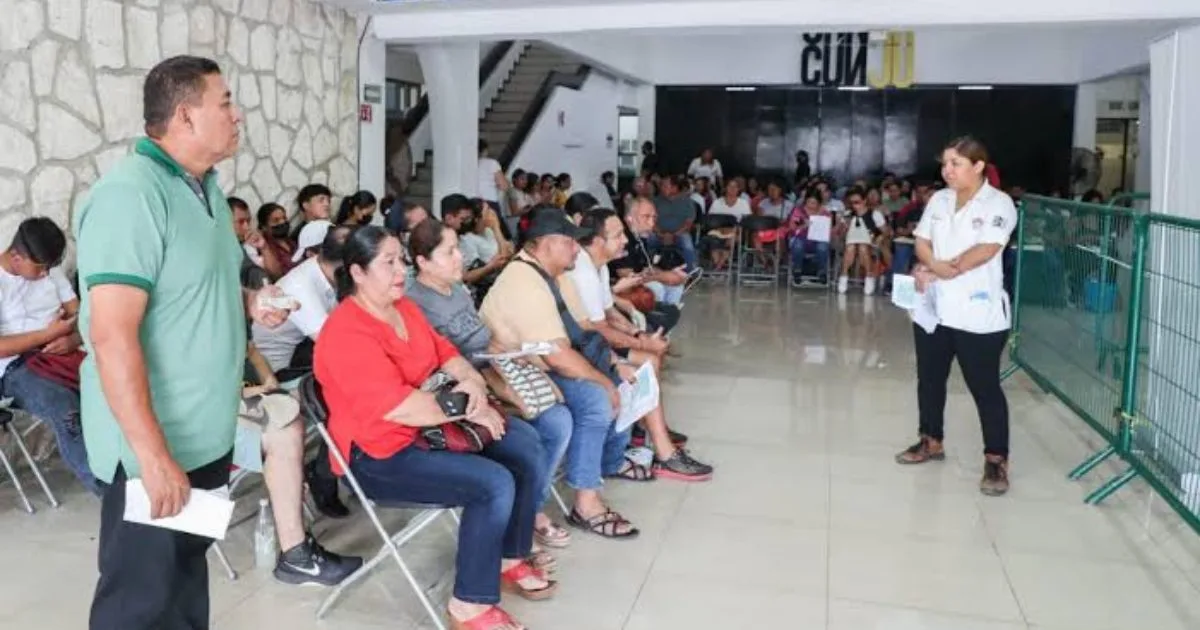 Contribuyentes en una fila haciendo trámites en un módulo móvil del SAT