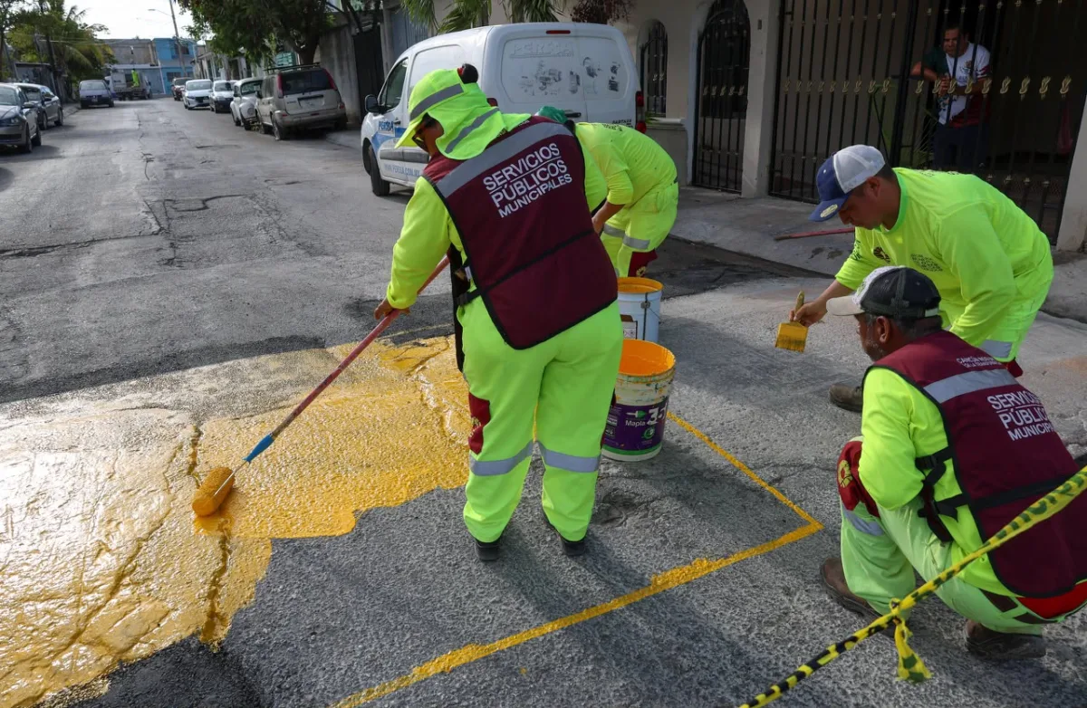 Workers painting a pedestrian crossing in Cancún with reflective yellow paint